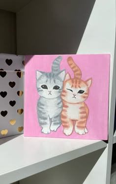 two cats painted on pink and white canvases with gold hearts in the back ground