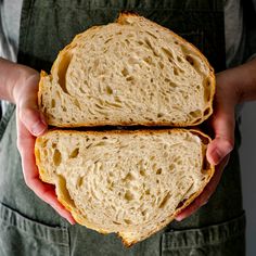 two pieces of bread in the hands of a person wearing overalls and an apron