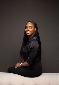 a woman sitting on top of a couch wearing a black shirt and pants with her legs crossed