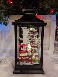 a lighted lantern sitting in front of a christmas tree with the words, you may not leave there