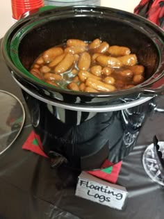 a large pot filled with lots of hot dogs on top of a table next to other items