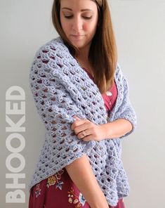 a woman wearing a blue crochet shawl and holding her hands on her chest