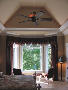 a bed room with a neatly made bed and a ceiling fan