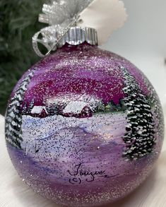 a purple ornament sitting on top of a table next to a christmas tree