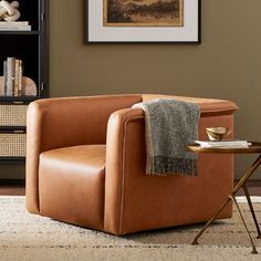 a living room with a chair, table and bookshelf on the wall next to it