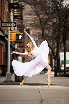 a woman in a white dress is dancing on the street