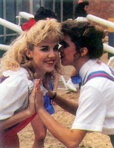 two people standing next to each other in front of a baseball dugout with bats