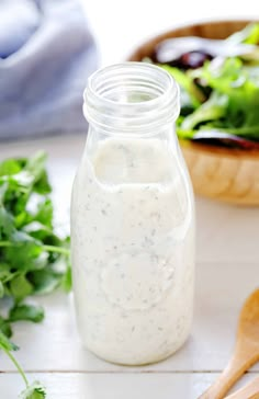 a jar filled with dressing next to a salad