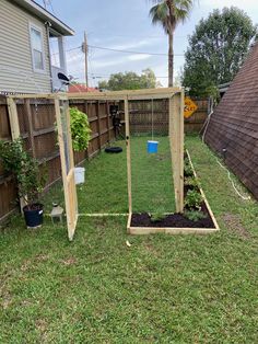 a backyard with a fence, potted plants and a chicken coop in the middle