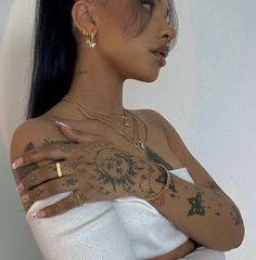 a woman with tattoos on her arms and chest is looking off to the side while wearing a white top