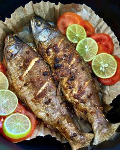 grilled fish with tomatoes, lemons and tomatoes in a paper bowl on a table