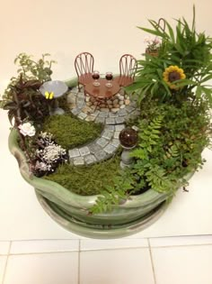 a potted planter filled with lots of green plants and small houses on top of it