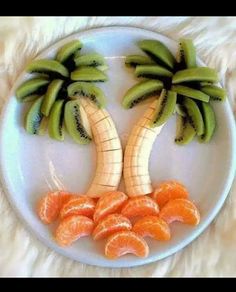 a white plate topped with bananas and oranges next to sliced up kiwi fruit