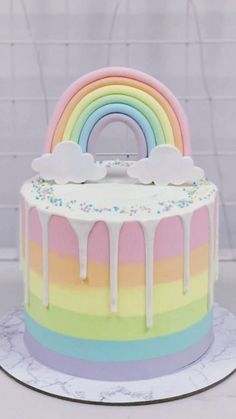 a rainbow cake with white icing and sprinkles on the bottom layer