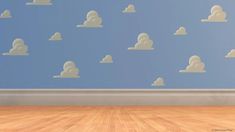 an empty room with blue walls and white clouds on the wall in front of it