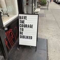 a sign that says have the courage to be disliked in front of a store