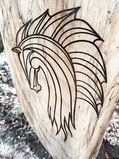 a wooden carving of a native american head on the side of a tree trunk with leaves around it