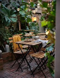 an outdoor table and chairs with lights hanging from the ceiling