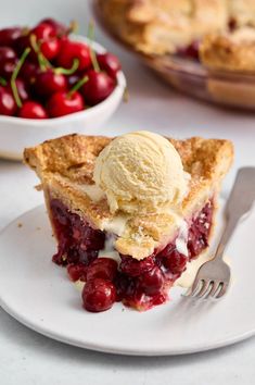 a piece of pie on a plate with ice cream and cherries in the background