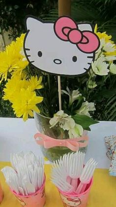 a hello kitty centerpiece on top of a table with flowers in vases next to it