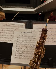 an instrument and sheet music are on display in a room with two people sitting behind it