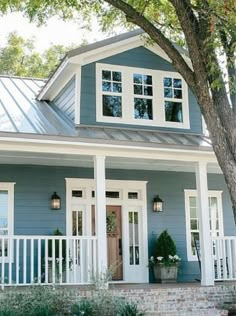 a blue house with white trim on the front door and porch, surrounded by trees