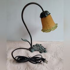 a lamp with a cord attached to it on top of a white sheet covered table