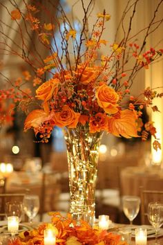 a vase filled with orange flowers on top of a table covered in white linens