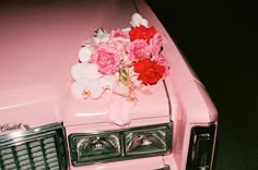 a pink car with flowers on the hood