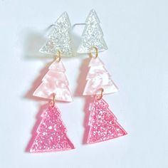 three pink and white triangle shaped earrings with glitter on the bottom, hanging from gold plated earwires