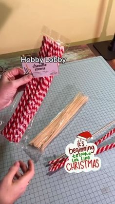 someone is wrapping matchesticks with red and white striped paper to make a christmas ornament