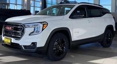 a white gmc suv is parked in a showroom