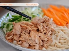 a white plate topped with meat and veggies next to carrots on a table