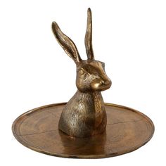 a golden rabbit figurine sitting on top of a wooden tray