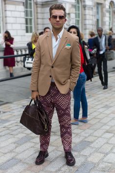 More menswear print play on the street at #LFW with ethnic-inspired geometric pattern trousers and a mismatched pocket square. And that grape colour works well with a pair pf oxblood shoes and holdall, all offset by a classic camel two-button jacket.  WGSN street shot, London Fashion Week Pattern Trousers, Grape Color, Mens Trends, High Fashion Street Style, Jacket Buttons, Fashion Pictures, London Fashion, Fashion Details, London Fashion Week