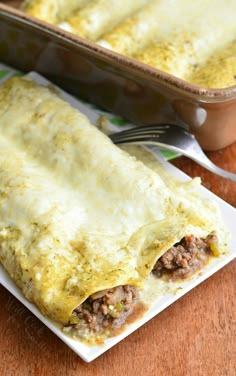 an enchilada sitting on top of a white plate next to a casserole dish