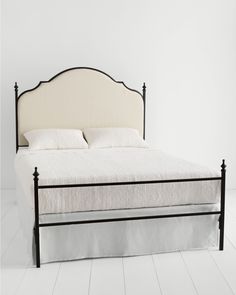 a white bed with black frame and headboard in a room that has white floors