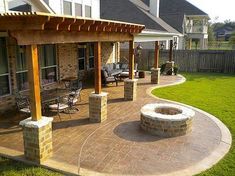 a patio with an outdoor fire pit and seating area in the back yard, surrounded by grass