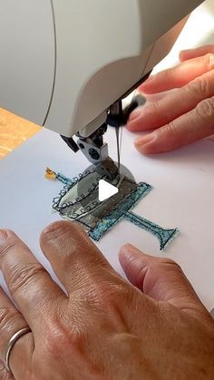 someone is using a sewing machine to sew the letters on paper that are placed in front of them