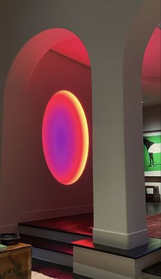 a room with arches and a round light in the center is lit by red lights