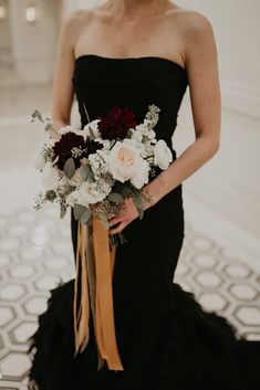 a woman in a black dress holding a bouquet