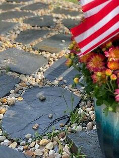 a vase filled with flowers sitting on top of a stone walkway next to an american flag