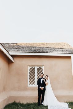 a bride and groom standing in front of a house