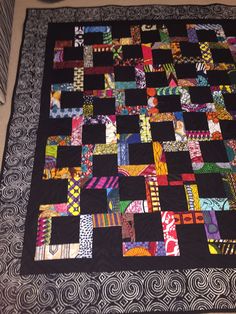 a black quilt with multicolored squares on it