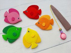 four felt fish and a knife on a white surface with some scissors next to them