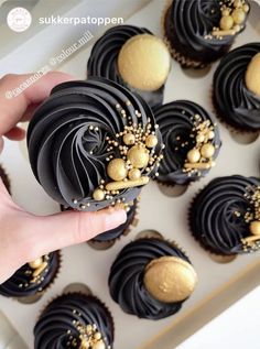 a hand holding a chocolate cupcake with gold sprinkles