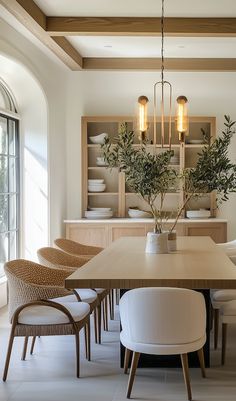 the dining room table is surrounded by white chairs and wooden shelves with plants in vases