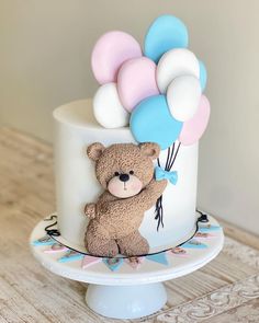 a birthday cake with a teddy bear and balloons