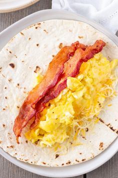 a tortilla with eggs and bacon on it