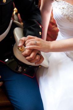 the bride and groom hold hands while sitting on a bench in front of other people